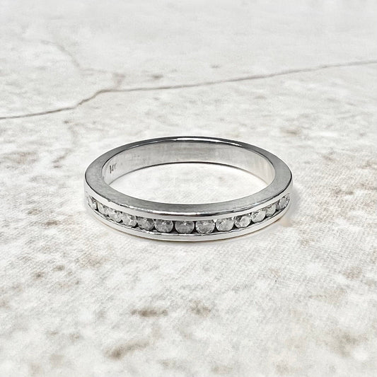A fine 14 karat white gold diamond half eternity band ring channel-set with 13 round diamonds weighing approximately 0.15 carat.